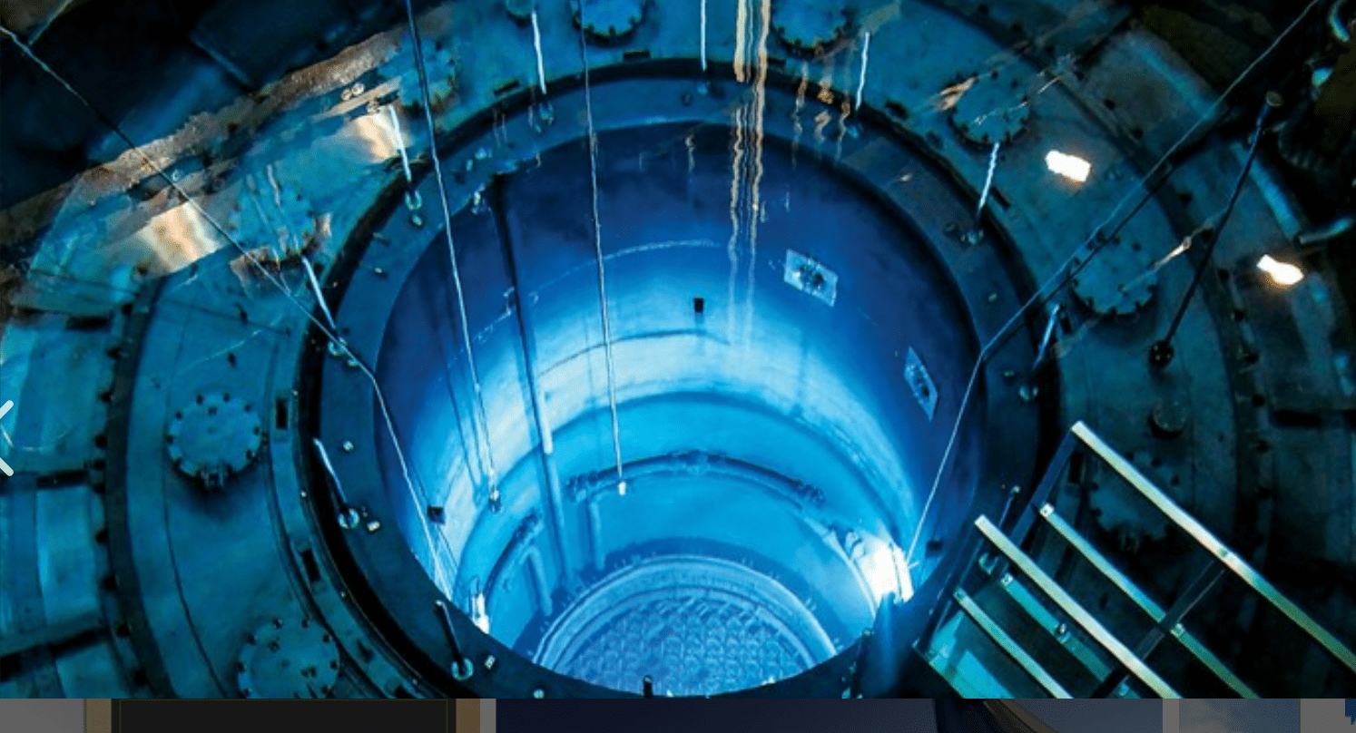 A high-angle view of a cylindrical structure illuminated in blue, revealing the interior of a nuclear reactor, highlighting nuclear reactor safety research by DIGBY D. MACDONALD.